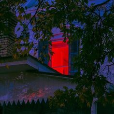 a red window is lit up in the night sky above a tree and house with its shutters open