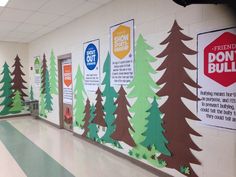 an empty hallway with trees painted on the wall and bulletin boards attached to the walls