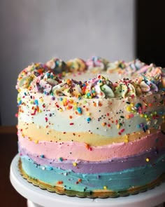 a multicolored cake with sprinkles on it sitting on a table