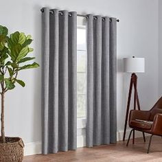 a living room with grey curtains and a brown chair