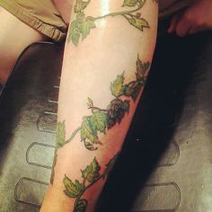 a person sitting down with a tattoo on their leg that has vines growing out of it