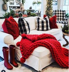 a living room filled with white furniture and red blankets on top of the couches