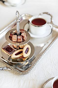 two trays filled with different types of food on top of a table next to cups and saucers