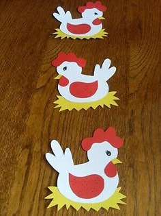 three paper cutouts of chickens on a wooden table