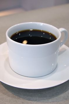 a cup of coffee sitting on top of a white saucer