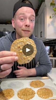 a man holding up a cookie in front of some cookies