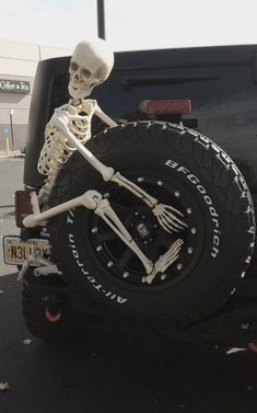 a skeleton sitting in the back of a pickup truck with its tire on it's flatbed