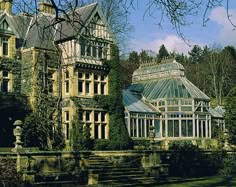 an old building with a glass roof and stairs leading up to the front door is surrounded by greenery