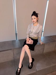 a woman sitting on some steps holding a pink purse and looking at the camera while wearing high heels