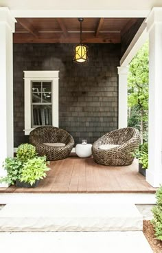 two wicker chairs sitting on top of a wooden porch