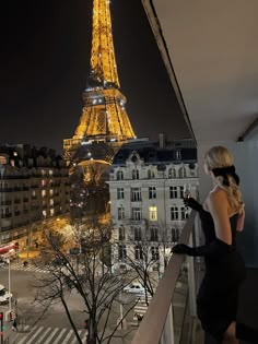 a woman looking at the eiffel tower from a balcony in paris, france