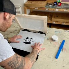 a man sitting at a table working on an art project with his hands in the box