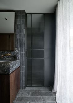 a bathroom with marble counter tops and dark wood cabinetry, along with a glass shower door