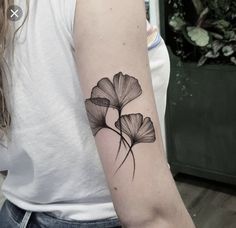 a woman's arm with a black and white flower tattoo on the left upper arm