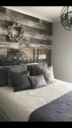 a bed with gray and white pillows on top of it next to a wooden wall