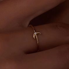 a woman's hand wearing a gold ring with an arrow on it and a diamond in the middle