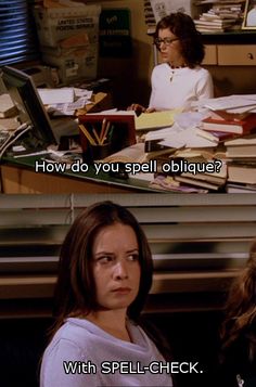 two women sitting at a desk with books on it and one has an open laptop