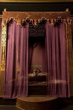 an elaborately decorated bed with purple drapes