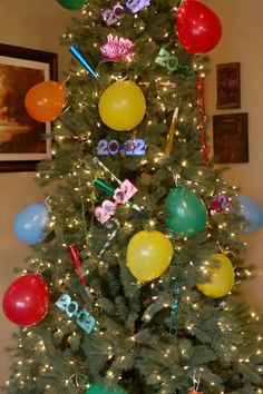 a decorated christmas tree with balloons and streamers in the shape of numbers on it