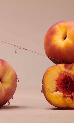 two pieces of peaches are tied to a string with water droplets on them and one piece has been cut open