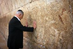 a man in a suit and tie standing next to a stone wall with his hands on it