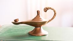 a brass teapot sitting on top of a green book