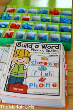 the build a word phonics spelling game is displayed on a table next to an open book