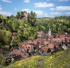 an aerial view of a small town in the countryside with trees and yellow flowers on the hillside