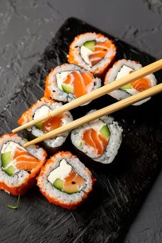 sushi on a black plate with chopsticks