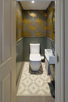 a white toilet sitting inside of a bathroom next to a sink and mirror on the wall