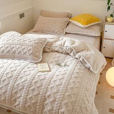 a white bed with two pillows on top of it and a lamp next to it