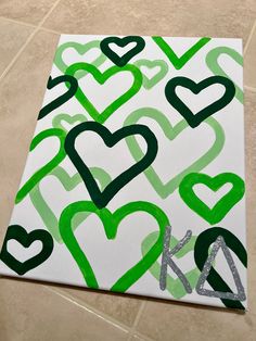 a painting with green and white hearts painted on it's canvases next to a tile floor