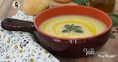 a red bowl filled with soup next to some pears and other fruit on a table