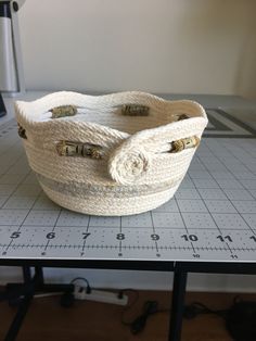 a white basket sitting on top of a table next to a cutting board with scissors