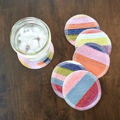 four coasters on a table next to a glass with ice in it and a jar