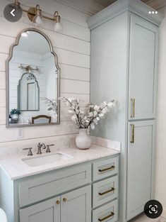 a bathroom with blue cabinets and marble counter tops, white walls and flooring is featured in this image