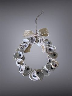 a wreath made out of seashells hanging from a string on a gray background