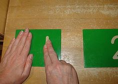 two hands are pressing the numbers on a green sign that says 2 and 3 in front of them