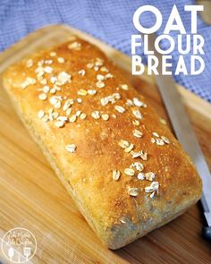 a loaf of oat flour bread sitting on top of a cutting board next to a knife