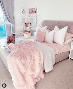 a bedroom with a large bed covered in pink fluffy blankets and pillows on top of it