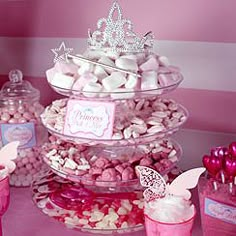 a table topped with lots of pink and white candy covered desserts on top of glass containers