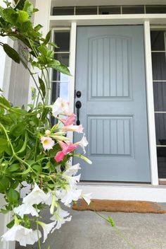 a blue front door with white and pink flowers