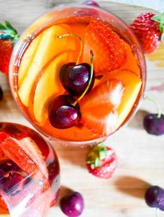 two glasses filled with fruit on top of a wooden table