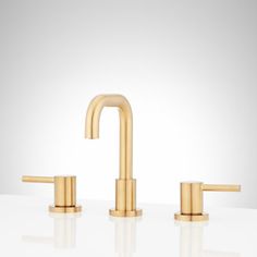 two gold faucets on a white surface