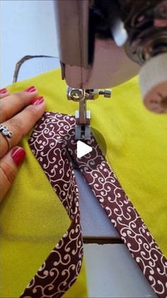 a woman is using a sewing machine to sew on a piece of fabric with her hands