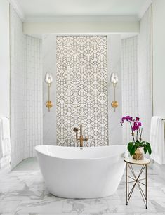 a white bath tub sitting in a bathroom next to a wall mounted shower faucet