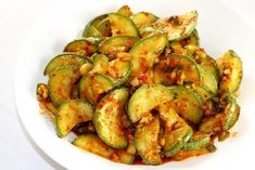 a white plate topped with sliced cucumbers covered in chili and seasoning sauce