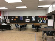 an empty classroom with desks, chairs and bulletin boards on the wall behind them