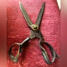 an old pair of scissors sitting on top of a red cloth