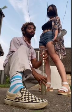 a man sitting on top of a pole next to a woman in shorts and socks